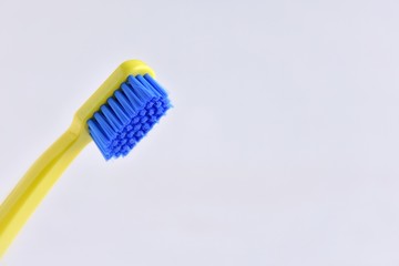Green toothbrush with blue bristles and selective focus on blurred neutral background with empty...