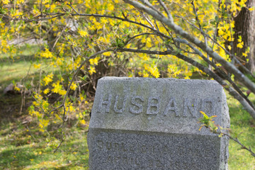 gravestone with  Husband on it with flower background. Concept of lost of spouse, widowness, getting old alone