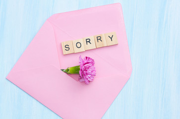 Word sorry, flower and envelope on blue background.