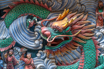Fototapeta premium Detail of a dragon statue on a wall in a Chinese temple in Singapore, closeup