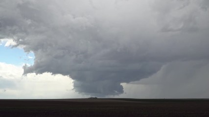 Severe thunderstorm over farm house as it tries to form a tornado in the Colorado plains as clouds spin in the sky.