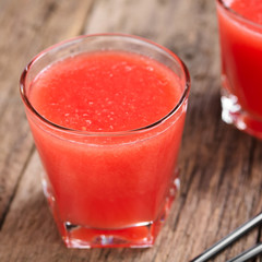 Refreshing watermelon juice on rustic wood (Selective Focus, Focus on the front of the glass rim)