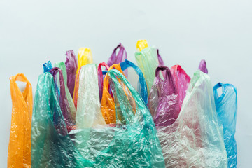 A bunch of disposable plastic multi-colored packages lie on a gray plane, a conceptual background on nature conservation with space for text.