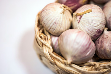 Garlic in a wicker basket, on a white background. Dried French garlic. Red garlic.