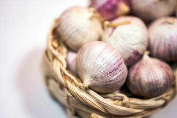 Garlic in a wicker basket, on a white background. Dried French garlic. Red garlic.