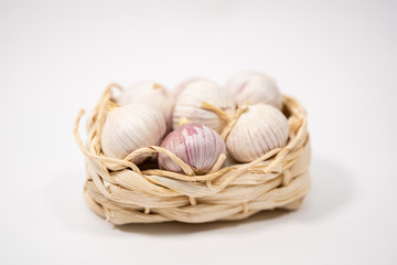 Garlic in a wicker basket, on a white background. Dried French garlic. Red garlic.