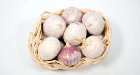 Garlic in a wicker basket, on a white background. Dried French garlic. Red garlic.