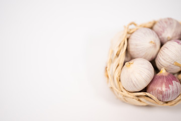 Garlic in a wicker basket, on a white background. Dried French garlic. Red garlic.