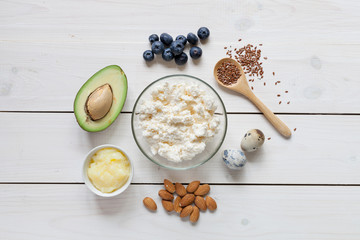 Ketogenic food concept with healthy fats: avocado, nuts, butter, berries, eggs, cheese.