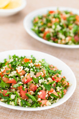 Fresh vegan Tabbouleh salad made of tomato, parsley, onion and couscous on plates (Selective Focus, Focus one third into the salad)