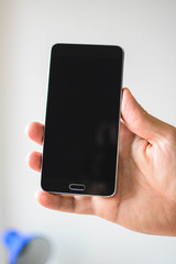 Mobile phone, smartphone in a hand isolated over grey background. Vertical. Copy space.