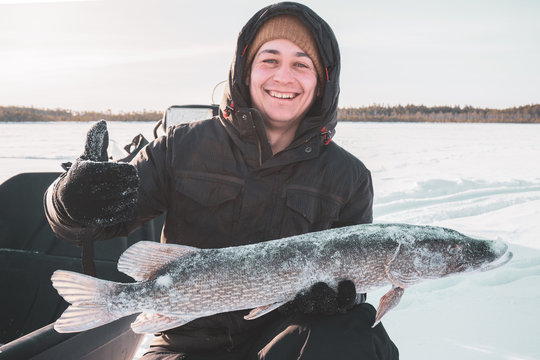 Young Man Holding Fish Catch A Big Pike Ice Fishing