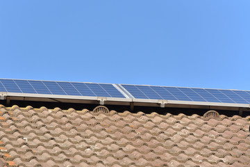 Solar panels installed on the roof of a house with tiles in Europe against the background of a blue sky. Green technology