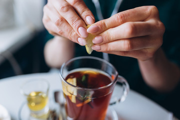 Girl drinking hot tea in cafe with honey, spices, mint, lemon and ginger. Breakfast, relax concept