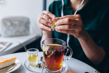 Girl drinking hot tea in cafe with honey, spices, mint, lemon and ginger. Breakfast, relax concept