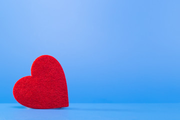 Fototapeta premium Bright red heart on a blue background in the left corner