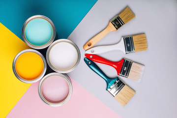 Four open cans of paint with brushes on bright background. Yellow, white, pink, turquoise colors of paint. Vertical photo. Renovation concept. - 272879256