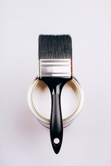 Brush with black handle on open can of white paint on grey background. Renovation concept. Top view.