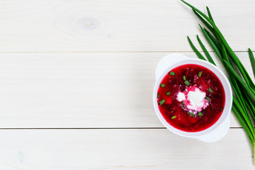 Borsch in a plate on a white wooden table, with copy space. Traditional, national russian soup.
