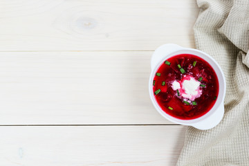 Borsch in a plate on a white wooden table, with copy space. Traditional, national russian soup.