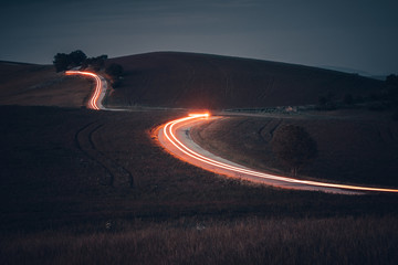 Light of car in night, dark hilly nature