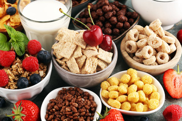 Cereal. Bowls of various cereals, berries and milk for breakfast. Muesli with kids cereals.