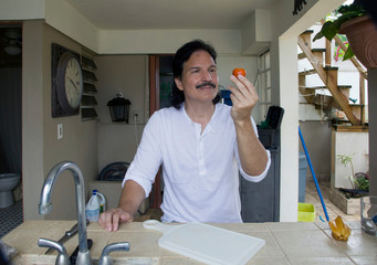 Hispanic man holding small tomato in hand - 272884081
