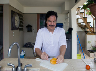 Hispanic man cutting star fruit with knife - 272884213