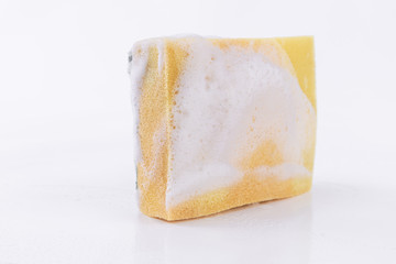 Close-up to the yellow side of a dish-washing sponge with foam