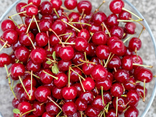 Ripe juicy red cherries in a transparent plate. A rich harvest of healthy berries. Natural vitamins. Photo view from the top.