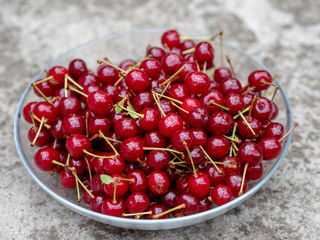 Ripe juicy red cherries in a transparent plate. A rich harvest of healthy berries. Natural vitamins. Photo view from the top.