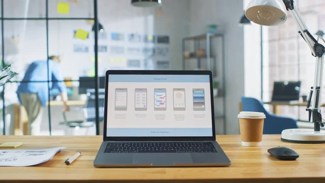 Laptop on the Desk in the Office Shows Screen with Mobile Phone Application Design, Software UI Development