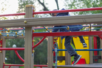 Fototapeta na wymiar brave boy playing on the playground and going down with ropes down