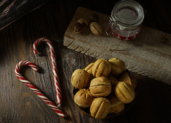 Food composition on a wooden background, consisting of dough nuts, in a coconut cup in combination with candy, a glass jar with hearts and pecan nuts.