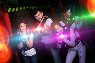 Young people on lasertag in colorful beams