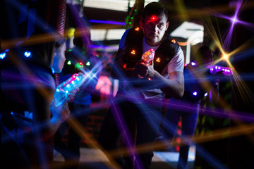 Fototapeta na wymiar Guy in colored beams during laser tag game