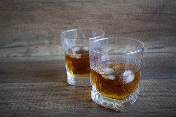 Bourbon Whiskey in a glass with ice on wooden table background