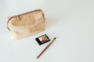 Golden cosmetic bag with cosmetic beauty products.