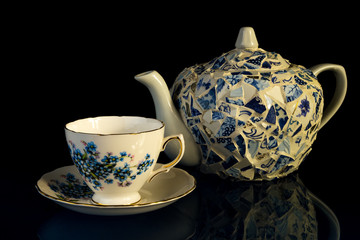 Tea Cup and Decorated Tea Pot on Black BG with Reflection in Glass Top Table