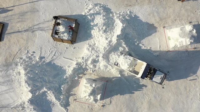 Overhead drone shot of construction workers shoveling and truck dumping snow in preparation of Harbin ice festival in China
