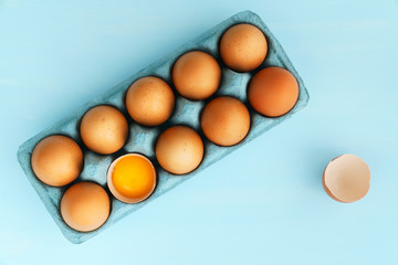 Close-up view of raw organic chicken eggs in a blue carton box. Blue background, high resolution