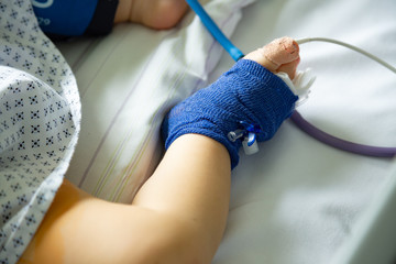 Foot of a sick child in hospital with peripheral venous line and pulse oximetry