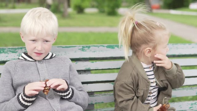 Children sit on a bench in the park. They hug and laugh