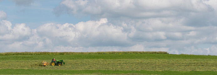 Fototapeta na wymiar Panorama of farmer tedding hay