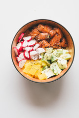 Hawaian trendy food of 2019 poke bowl, with radish tuna, salmon, jasmine rice, avocado, top view over a concrete gray backdrop, with mall bowl with ingredients, soya sauce, sesame, japanese hawaian ty