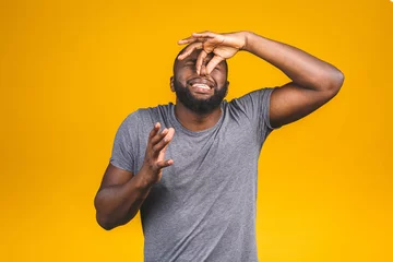 Foto op Canvas Afro american man isolated against yellow background smelling something stinky and disgusting, intolerable smell, holding breath with fingers on nose. Bad smells concept. © denis_vermenko