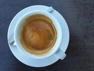 Coffee cream with foam on a dark stone table - top view