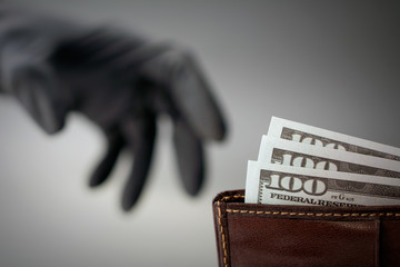a black-gloved thief steals money from a wallet. concept of danger of theft robbery financial...