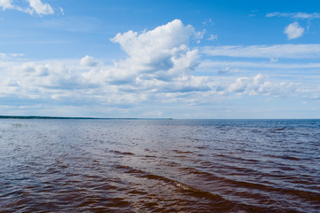 Obraz premium Lake Ladoga in the summer sunny day, reveals its open spaces for tourists. Clear water, combined with orange sand at the bottom of the lake, shows the bright boundaries of the depth of the lake.