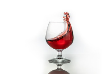 Red wine splashing out of a glass, isolated on white. Concept: alcoholic drinks